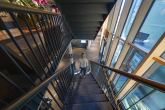 Woman descending a modern staircase in a building surrounded by large windows, Amazonia exhibition,
