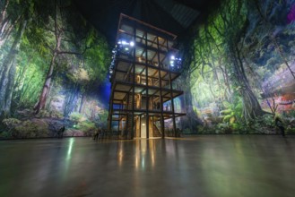 A multi-storey timber building in a glowing green artificial forest installation, Amazonia