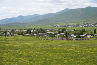 Village in green landscape with meadows and mountains in the background, view of Geghamavan,