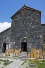 Old stone building with open door and roof under blue sky, cross stones at Sevanavank monastery,