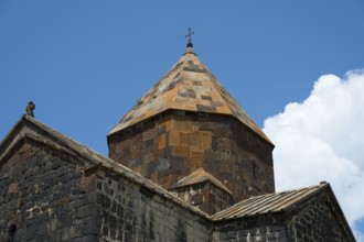 Close-up of a stone church tower with a detailed roof under a blue sky, Sevanavank monastery, Sevan