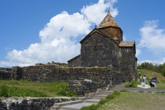 Historic stone monastery under cloudy sky in a green landscape, Sevanavank monastery, Sevan