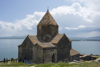 A historic monastery rises above a lake, with mountains in the background, Sevanavank monastery,