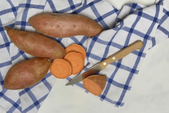 Sweet potatoes with kitchen knife on kitchen towel, Ipomoea batatas