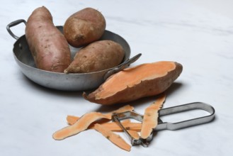 Sweet potatoes in skin and potato peeler, Ipomoea batatas