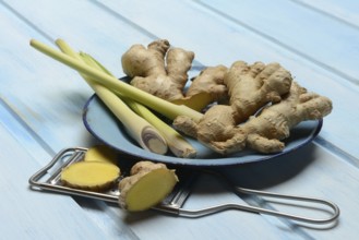 Ginger tubers and lemongrass on plate, grater with ginger pieces