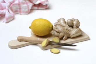 Ginger root and lemon on cutting board with knife, ginger slices, Zingiber officinale