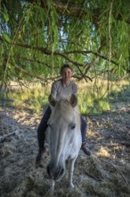 Young girl sitting on her horse under a tree, Othenstorf, Mecklenburg-Western Pomerania, Germany