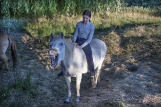 Young girl rides on her whining white mare in the moor area, Othenstorf, Mecklenburg-Western