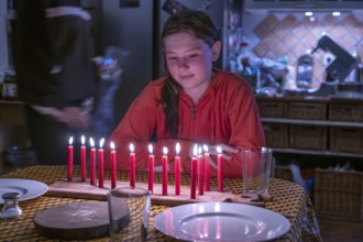 Young girl sitting at the table in front of her thirteen burning birthday candles, Othenstorf,