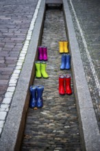 Colourful rubber boots in dry watercourse, Freiburg im Breisgau