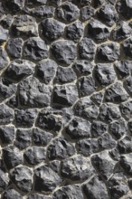 Detail of a wall of black, irregular rocks