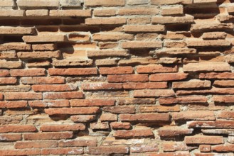 Irregular, old brick wall in rusty shades