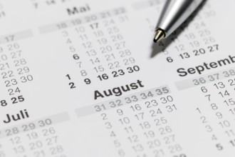 Close-up of a calendar with ballpoint pen pointing to the month of August