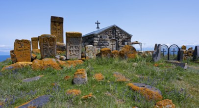 Historic chapel and tombs with stone crosses on a grassy hill, khachkars at the chapel of the Holy