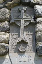 Historic stone cross with engravings and decorated architecture embedded in a stone wall, Chapel of