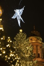 An artist hovers on a crane over the Christmas tree in front of the German Cathedral at the