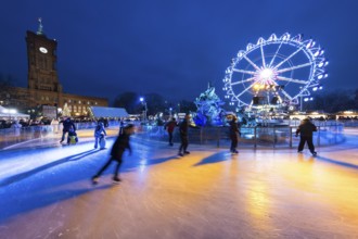 Skaters in front of the Red Town Hall, Neptune Fountain and a Ferris wheel at the Berlin Christmas