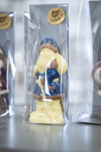White and blue chocolate Santa Claus figure in transparent packaging on a table, Christmas baking,