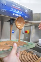 A ladle pours chocolate from a machine into green chocolate molds, Christmas baking, Haselstaller