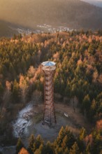 An observation tower overlooks a dense, autumnal forest near a village, Hohe Warte observation