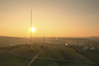 A sunset over countryside and fields with a distinctive transmission tower in the foreground,