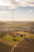 A tall radio tower rises above an autumn landscape with a small town in the background, MÃ¼hlacker,