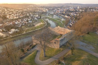 A historic castle overlooks a river and urban structures at dusk, MÃ¼hlacker, Enzkreis, Germany