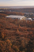 Factory building next to an autumn forest, with urban environment in the background, MÃ¼hlacker,