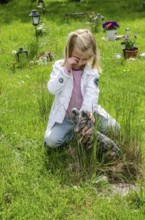 Grieving blonde 7-year-old girl at her dog's grave at pet cemetery in Ystad, SkÃ¥ne County, Sweden,