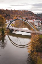 Bridge over a river in an autumn landscape, houses in the background and reflection in the water,