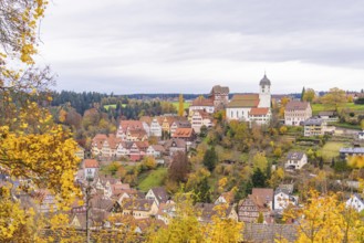 Panorama of a traditional town with church tower, surrounded by autumn landscape and fields,