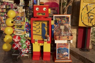 Old town of Nauplion, A colorful robotic toy machine next to yellow balloons at a street stand,