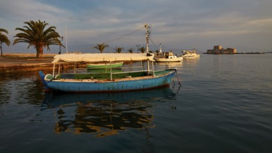 Port of Nauplion, Bourtzi island fortress, A blue boat in the harbor with palm trees and view of a