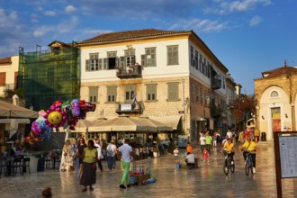 Old town of Nauplion, lively town square with cafés, people, bicycles and colorful balloons at