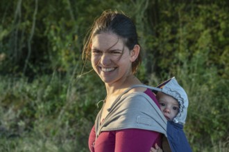 Young mother carrying her baby in a shawl on her back, Othenstorf, Mecklenburg-Western Pomerania,