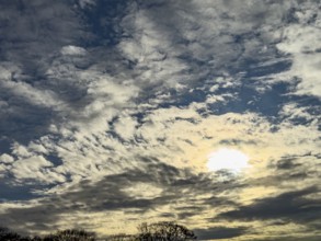 Altocumulus fractus cluster clouds in the lower half of the image Sun shines through Altostratus