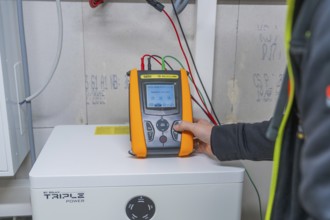 Person holds meter on a solar panel to check performance