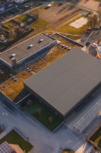Sports center and swimming pool with flat roof and adjacent parking lot, surrounded by green areas