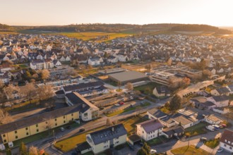 Aerial view of a settlement in warm evening light with hills and landscape in the background,