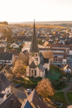 Bird's eye view of a village with a church in the center, surrounded by blooming trees and houses