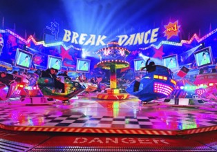 People in the colorful illuminated break dance ride at night at the All Saints Fair, Soest, North