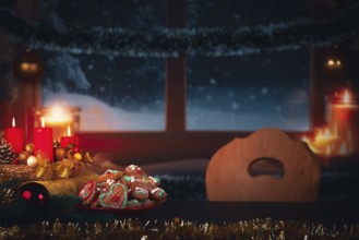 Festively decorated table with candles and cookies in front of a snowy window at night