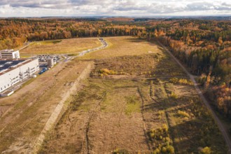 Wide, empty area next to sparse forest and industrial plant in an autumnal setting, new Lindenrain