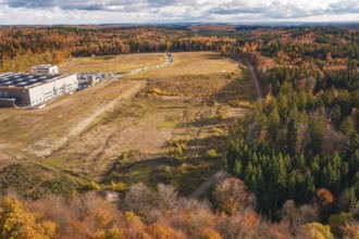 Industrial plant in autumn, surrounded by diverse forest in an open landscape, new Lindenrain