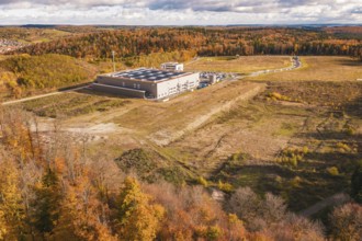 Aerial view of an industrial building surrounded by autumn forest and open fields, new Lindenrain
