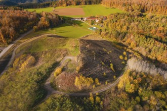 Hilly autumn landscape with colorful trees and fields, farm and winding paths, new Lindenrain