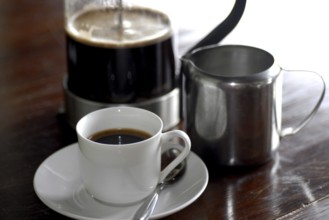 French coffee press next to a cup of coffee and a milk jug on a table, Serenity boutique hotel,