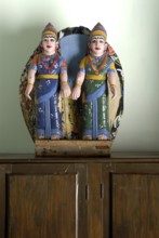 Two painted wooden female figures in traditional South Indian clothing, sari, standing on a closet,
