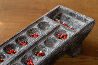 Traditional wooden game Pallankujhi, Pallamkuzhi, Pallangulli, Pallankulli or Alagulimane with red